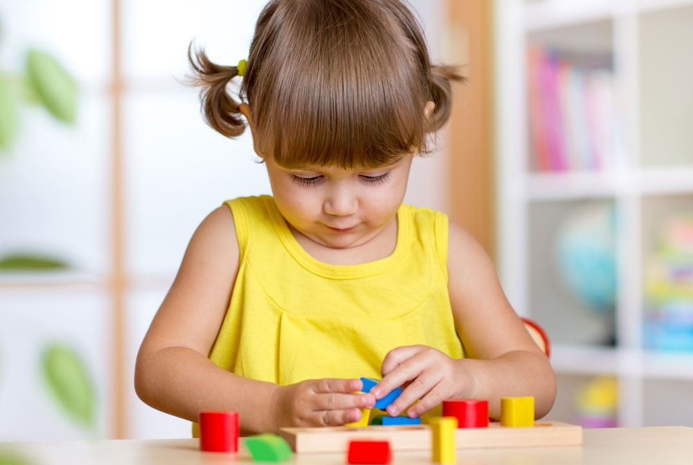 Kind spielt mit Holzspielzeug im Rahmen einer ergotherapeutischen Sitzung